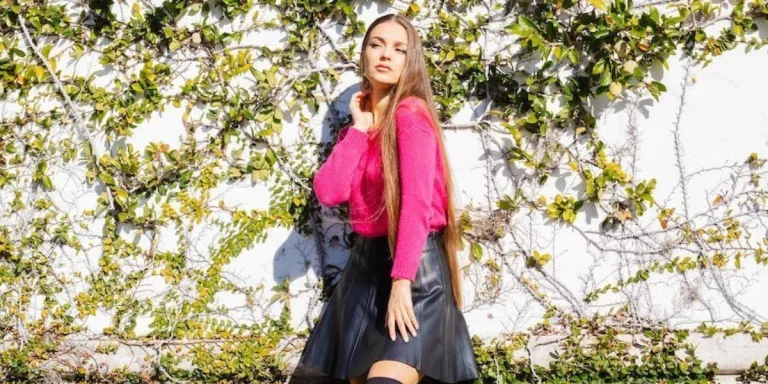 Lady posing near a wall in a black leather skirt