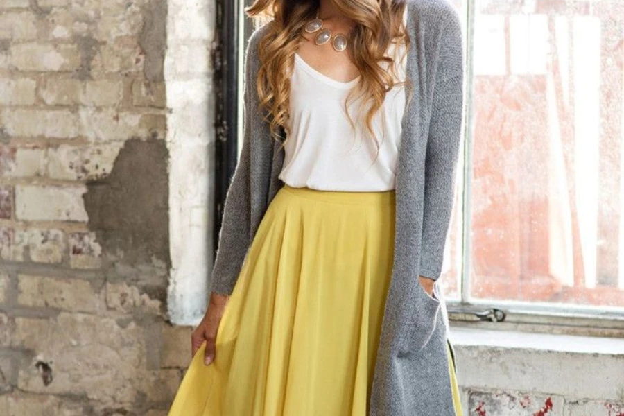 Lady showing off a gray sweater and yellow maxi skirt