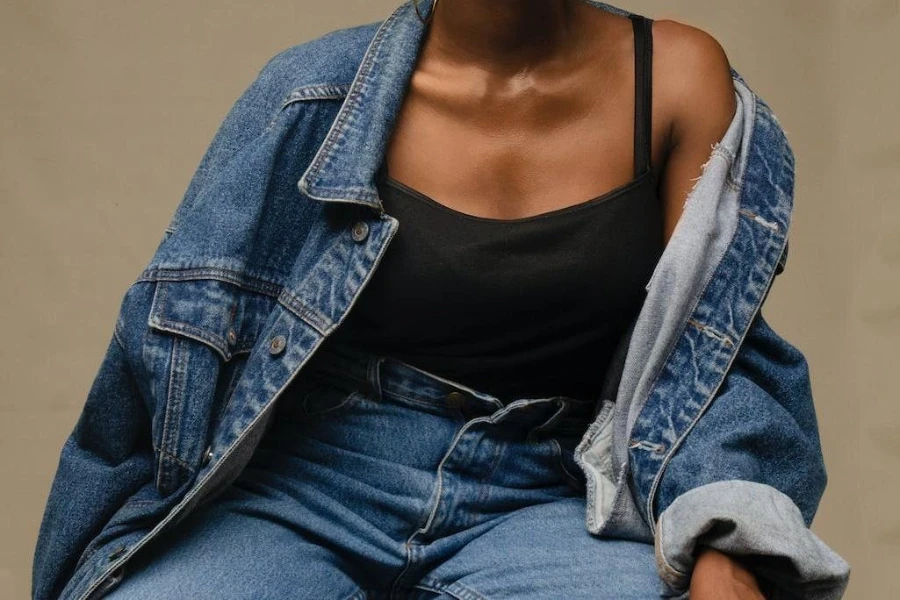 Wanita mengenakan jaket denim dan celana panjang dengan singlet hitam