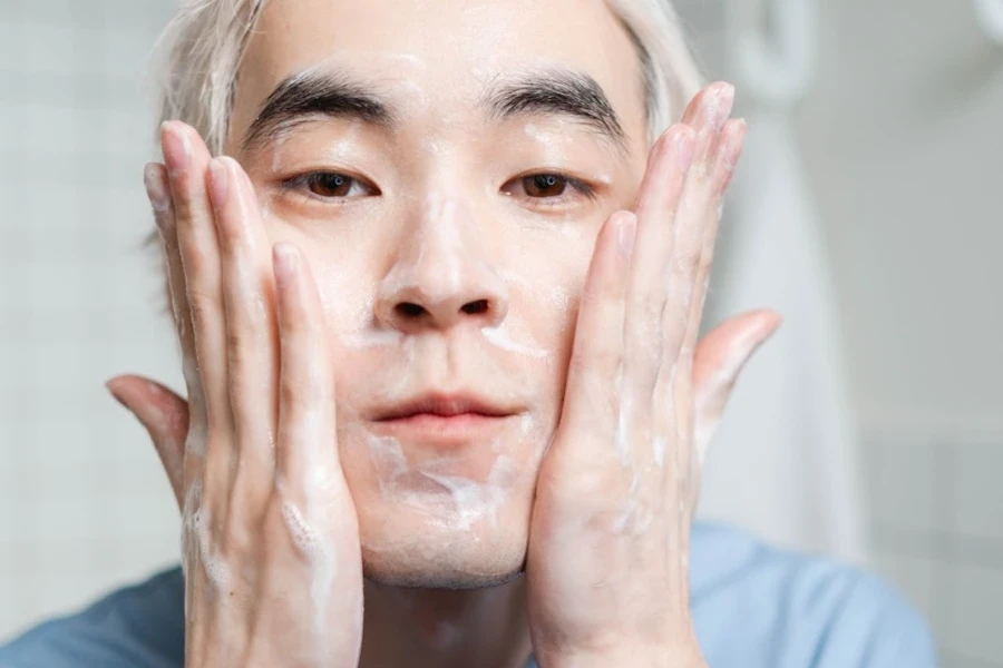 Homme appliquant une crème hydratante dans le miroir