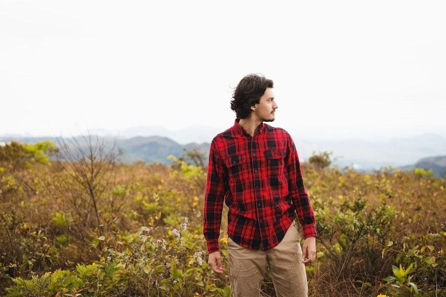 Homem em um campo vestindo uma camisa xadrez vermelha