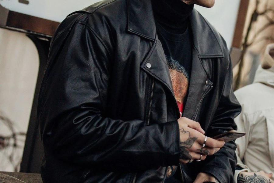 Man in an oversized leather jacket holding a phone