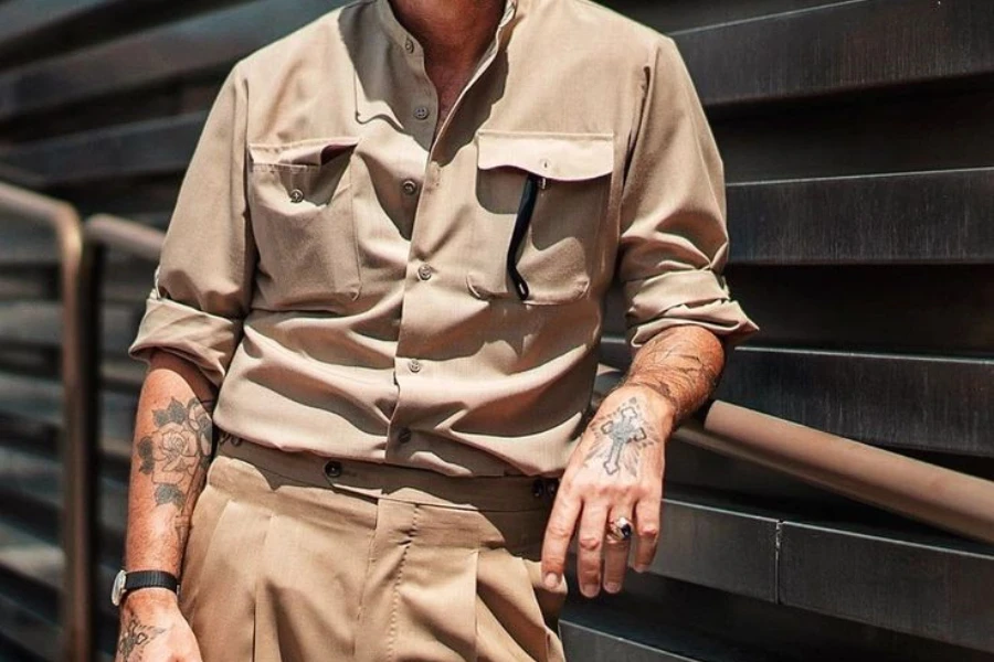 Uomo in camicia safari e pantaloni color kaki appoggiati sulle ringhiere