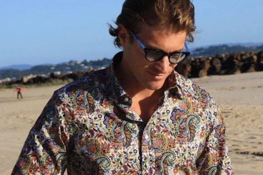 Man on a beach rocking a paisley shirt