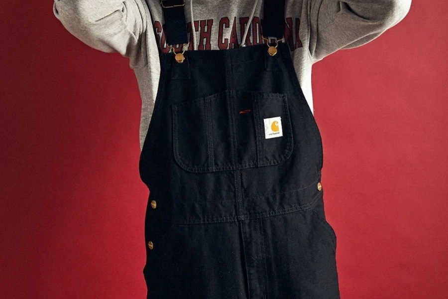 Homem posando com um macacão jeans escuro e elegante