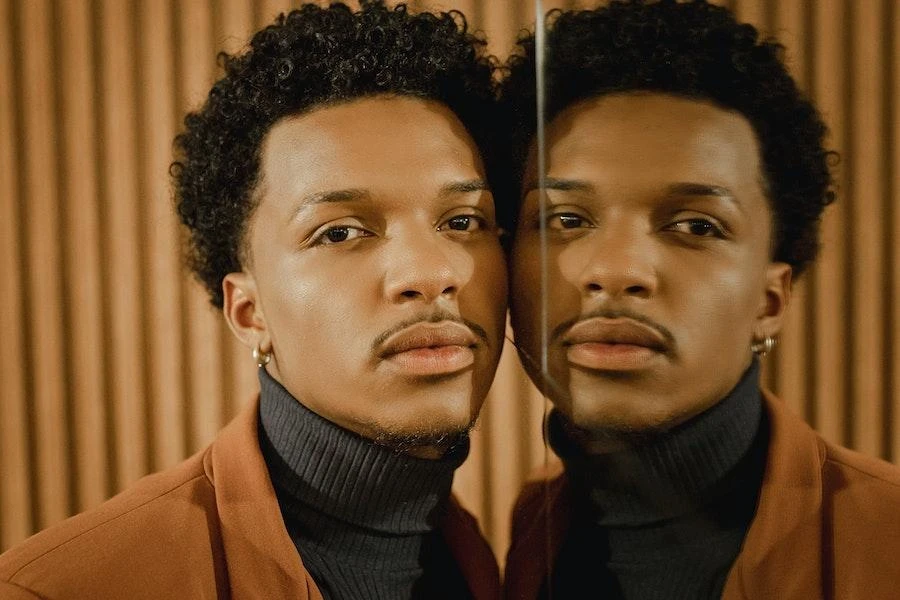 Man posing with his reflection in a black ribbed turtleneck