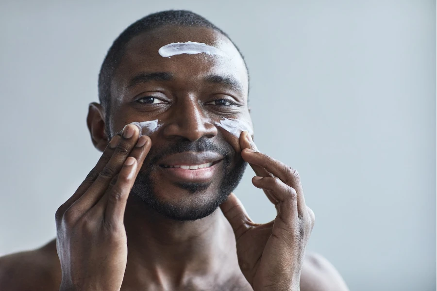 Mann trägt Feuchtigkeitscreme auf sein Gesicht auf