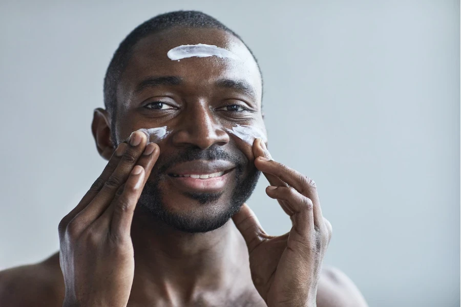 Hombre poniéndose crema hidratante en la cara