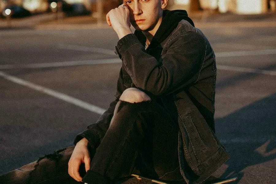 Man sitting on a floor wearing black ripped jeans