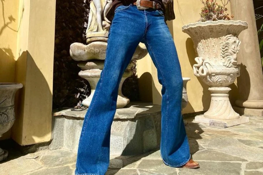 Man stylishly posing in blue bell-bottom jeans