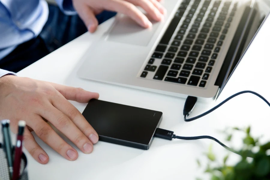 Homme utilisant un disque dur externe pour sauvegarder des fichiers