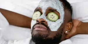 man wearing a face mask and cucumbers on his eyes