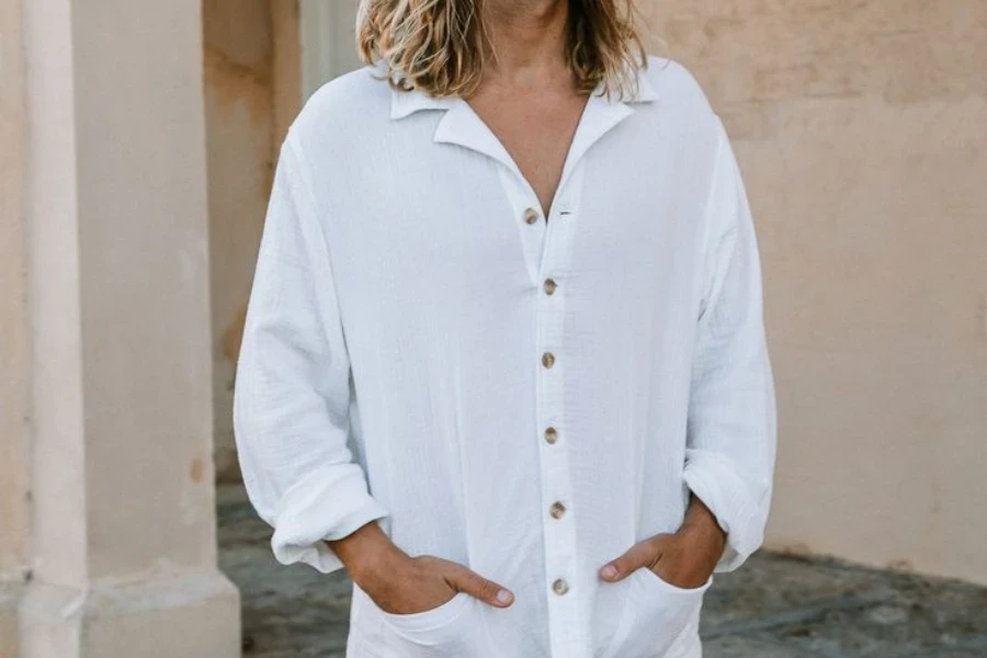 Hombre con las manos en los bolsillos de una camiseta Henley blanca.