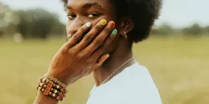 Man with painted nails holding his hand against his face