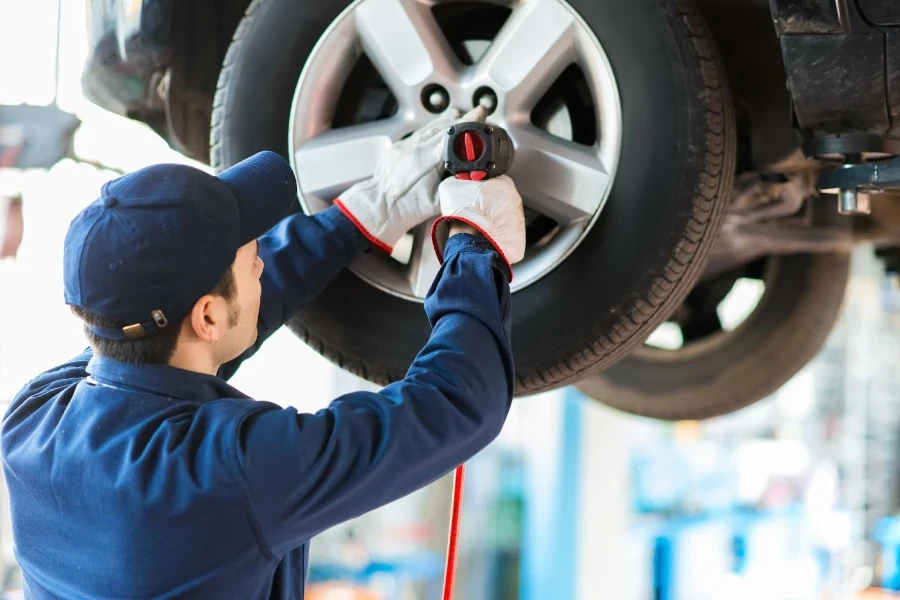 Meccanico che cambia la ruota dell'auto in un'officina riparazioni auto