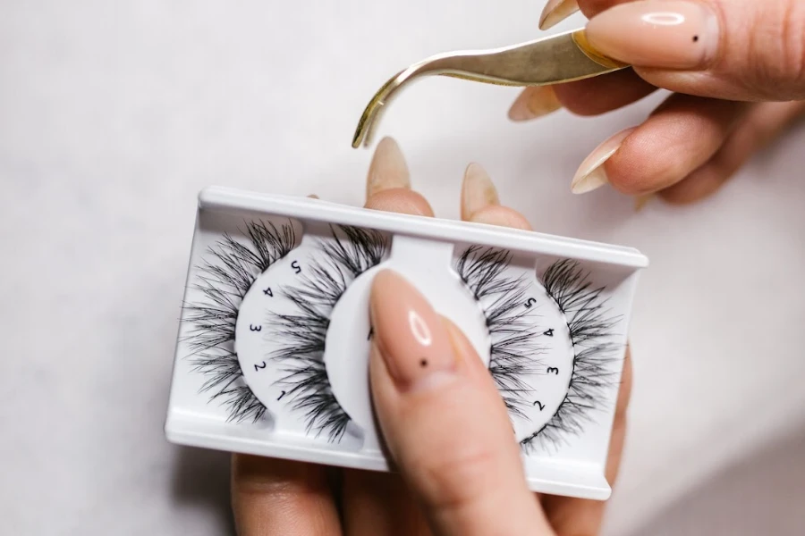 Person holding cat eyelashes and tweezers to apply them