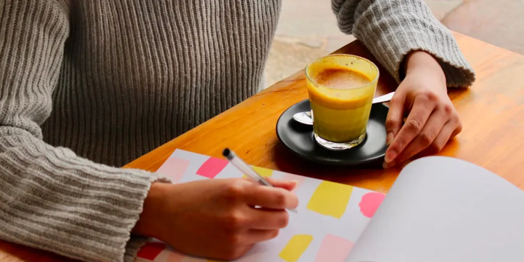Person with a cup of coffee planning on a notepad