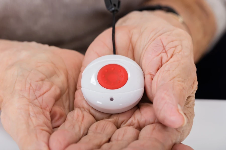 Senior with wrinkled hands holding a medical alert device