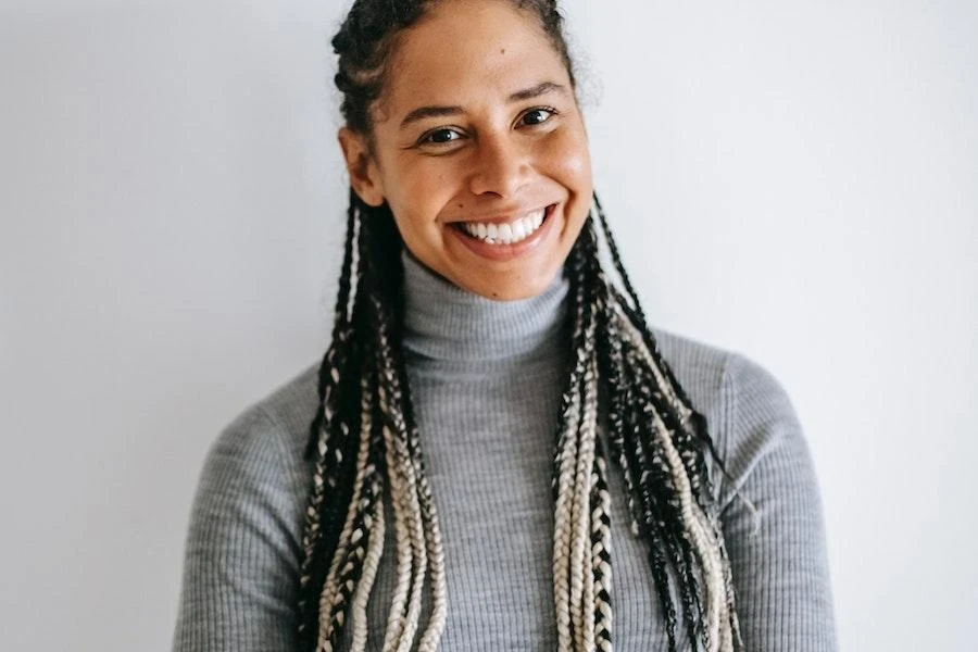 Mujer sonriente vistiendo un jersey de cuello alto acanalado gris