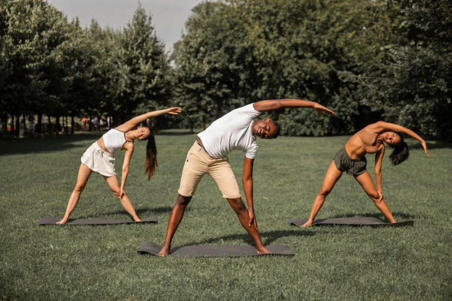 Três pessoas se alongando no parque