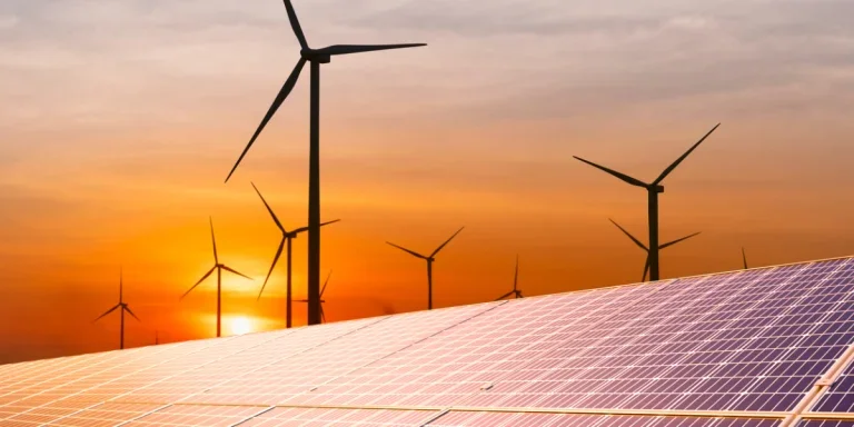turbina eólica y un panel solar al atardecer