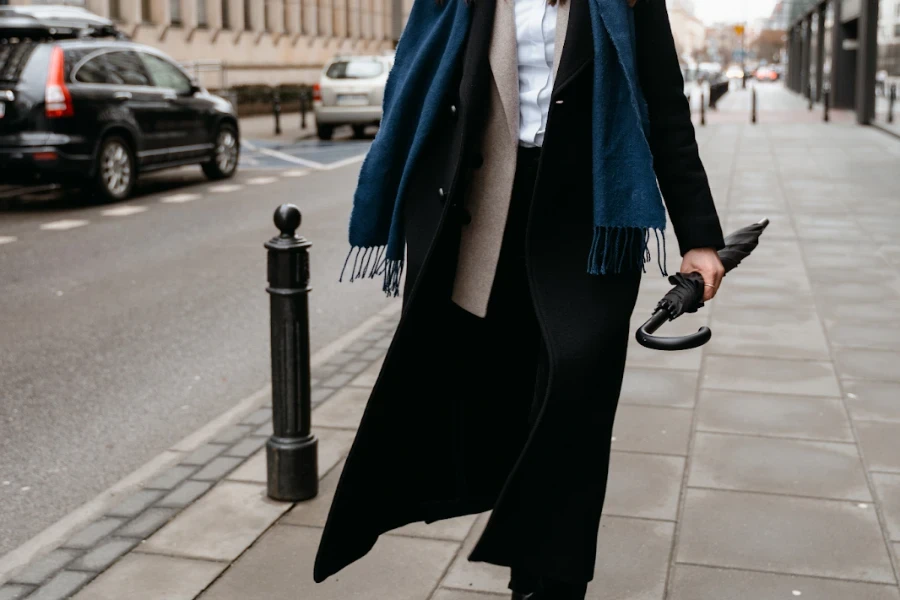 Woman holding an umbrella rocking a long black coat