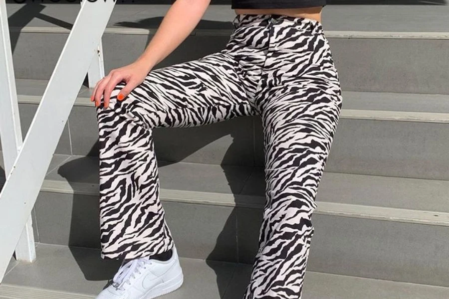 Frau in einer Bootcut-Jogginghose mit Animal-Print sitzt auf einer Treppe