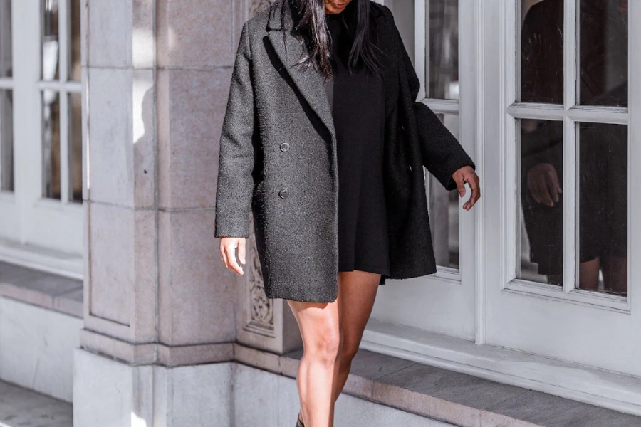 Woman posing in a short black oversized coat