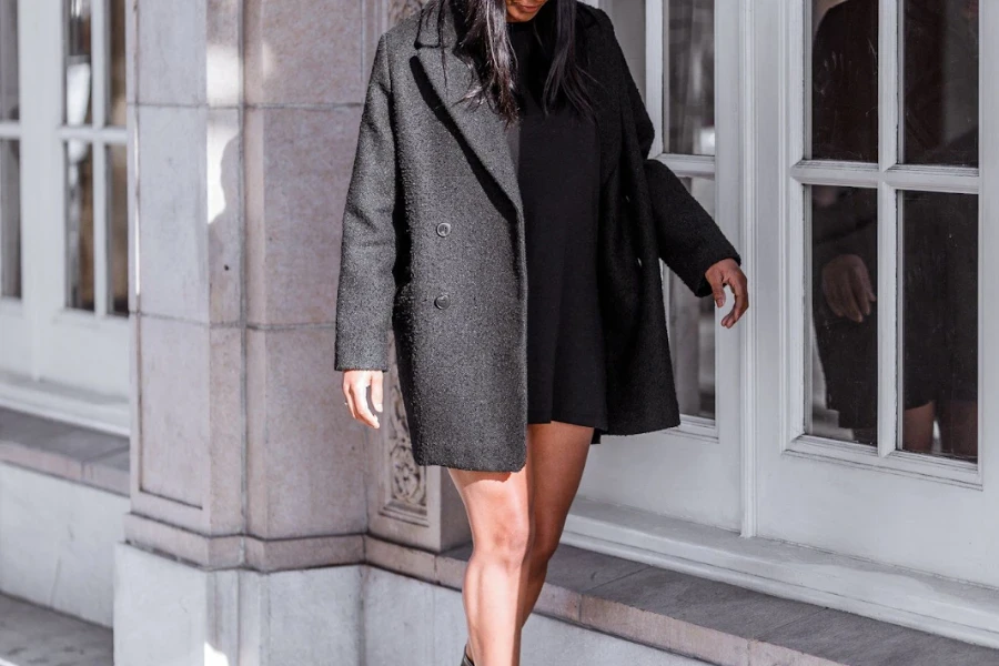 Donna in posa in un corto cappotto oversize nero