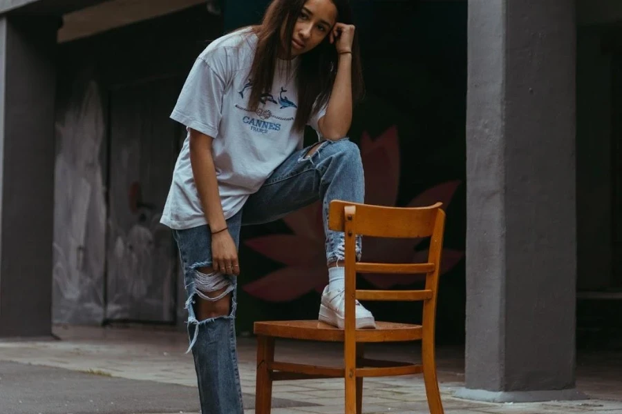 Woman posing with a chair in a white graphic top