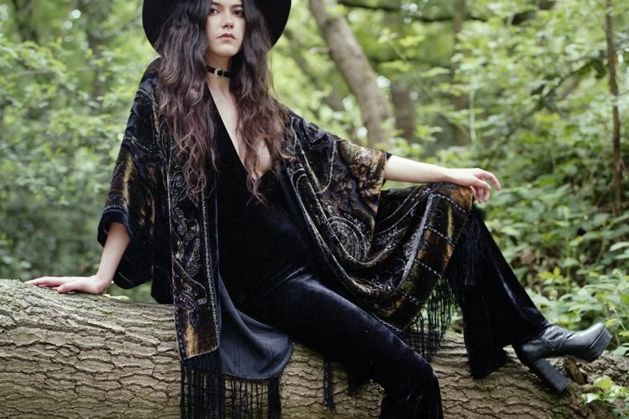 Woman sitting on a log in boho-witch attire