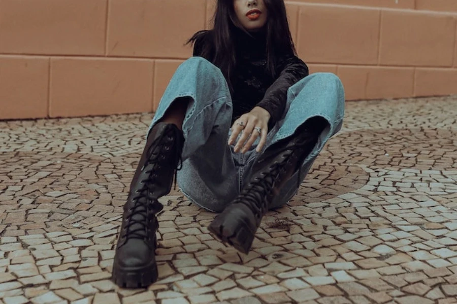 Woman wearing combat boots sitting on a sidewalk