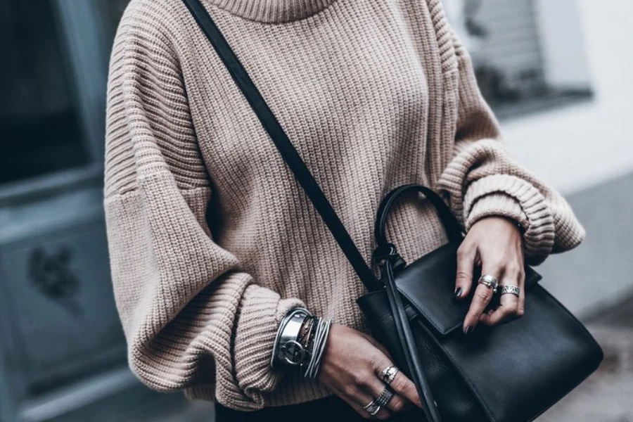 Woman with a bag wearing an oversized knitwear and jeans
