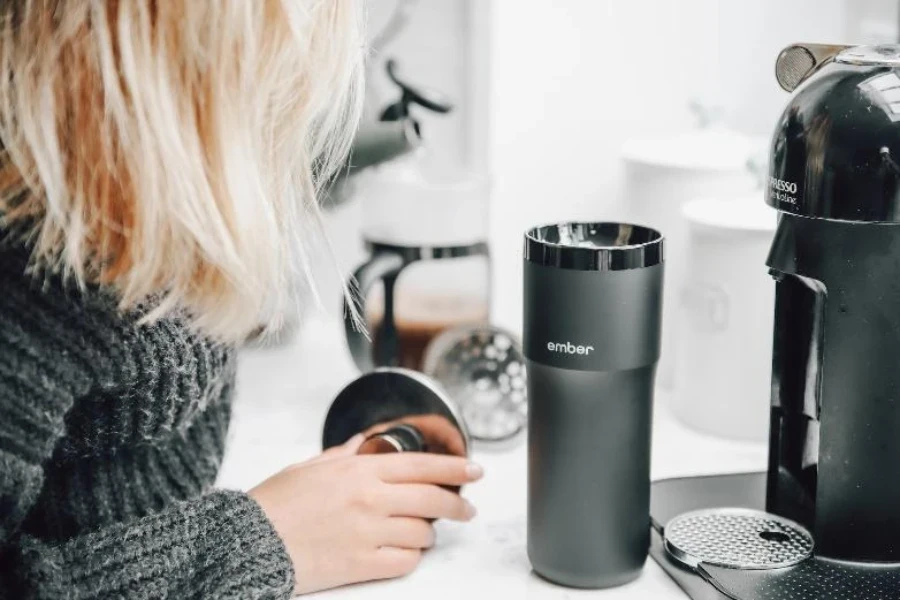 Mujer con vaso de viaje gris y plateado