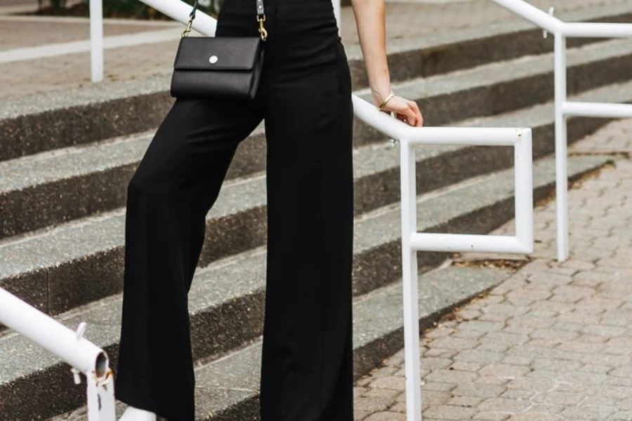 Lady in black slacks posing near staircase