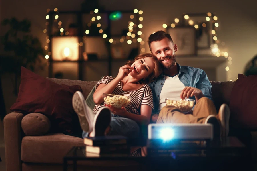 Um casal assistindo a um projetor de televisão em casa