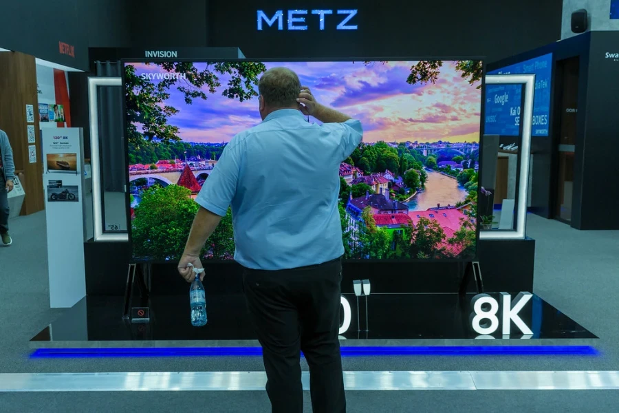 un homme debout devant une télévision 8k