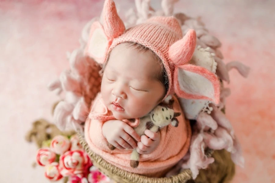 A newborn baby wrapped in an orange swaddle and hat