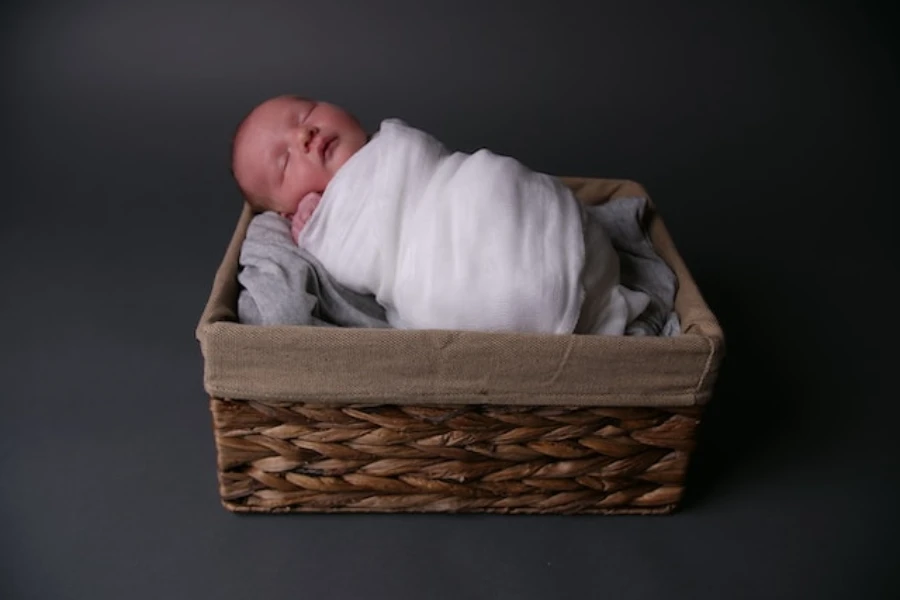a newborn wrapped in a white swaddle in a basket