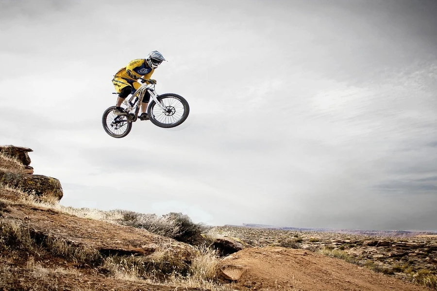 A person jumping off a hill on mountain bike