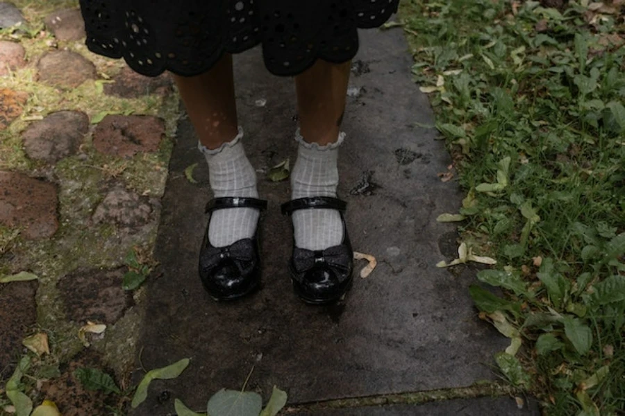 Un estudiante con zapatos escolares negros y calcetines blancos.