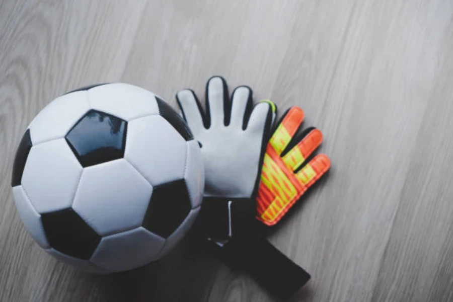 Black and white football next to bright goalie gloves