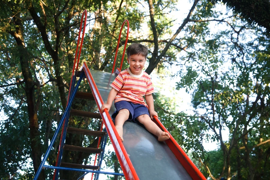 Boy using a straight playground slide detached from jungle gym