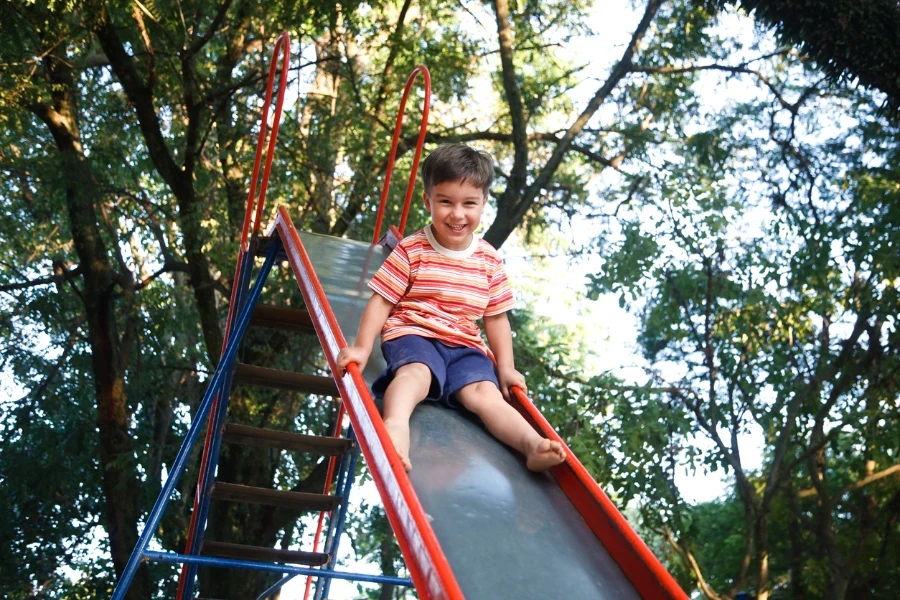 Boy using a straight playground slide detached from jungle gym