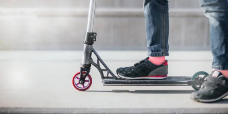 Child standing on black scooter with dark pink wheels