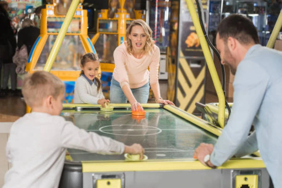 Famille utilisant une table de hockey sur air standard à l'intérieur d'une salle de jeux vidéo