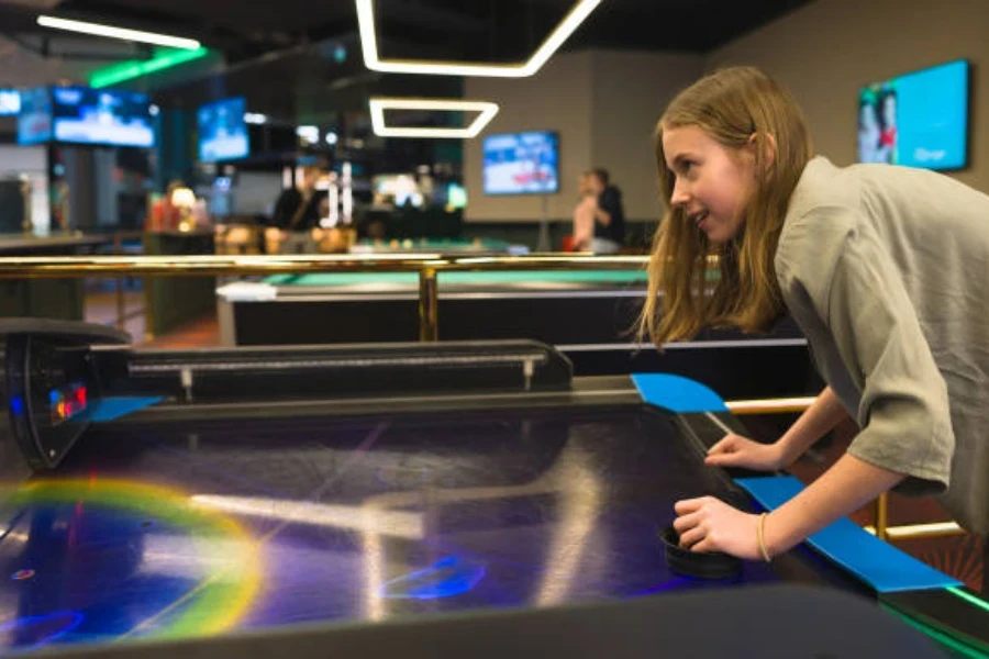 Fille utilisant une table de hockey sur air commerciale à l'intérieur d'un espace de jeu