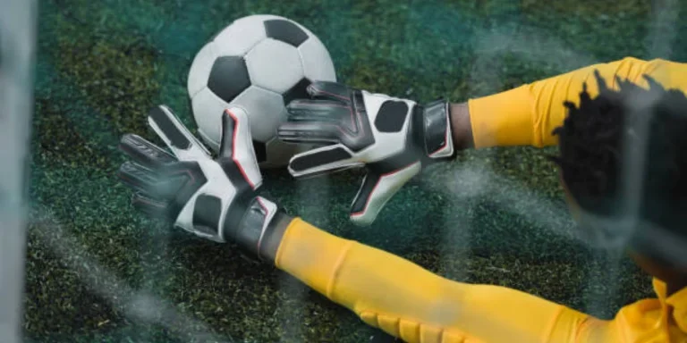 Goalie in yellow stopping football before it goes in