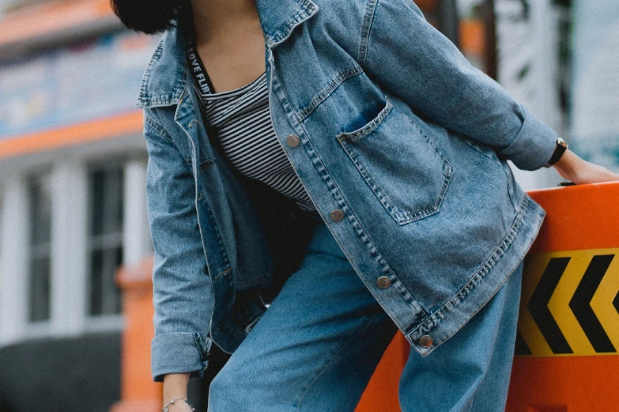 Eine Dame in einer übergroßen Jeansjacke beugt sich vor