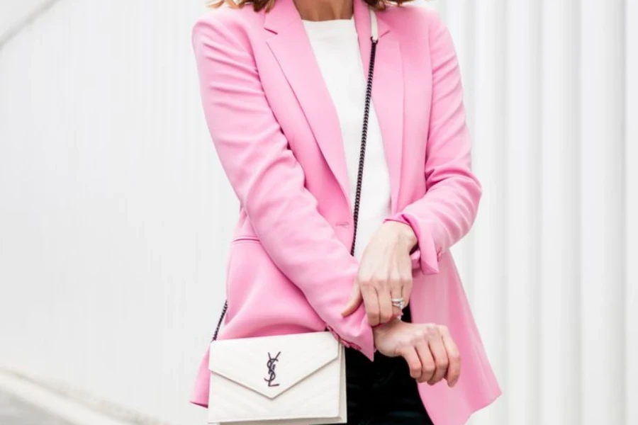 Lady folding the sleeves of a pink preppy jacket